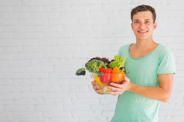 Foto gratuita joven sosteniendo verduras frescas en recipiente de vidrio