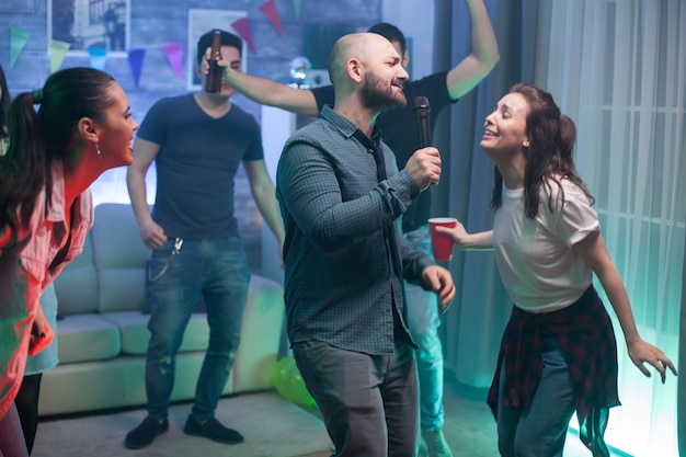 Foto gratuita joven y su mejor amigo cantando en el micrófono en la fiesta.