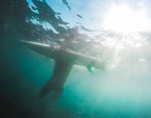 Joven con tabla de surf en agua azul