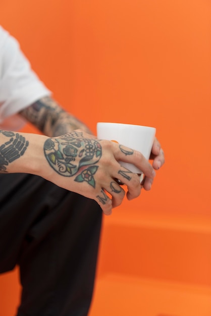 Foto gratuita joven con tatuajes disfrutando de una taza de café en la cafetería.