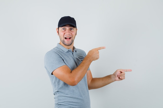 Joven técnico apuntando hacia el lado derecho en uniforme gris y mirando alegre.