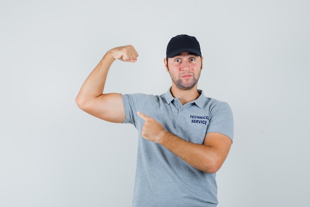 Foto gratuita joven técnico apuntando a los músculos del brazo en uniforme y mirando confiado.