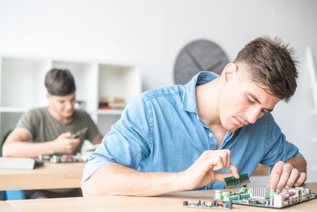 Joven técnico informático masculino fijación de RAM en la ranura de la placa base