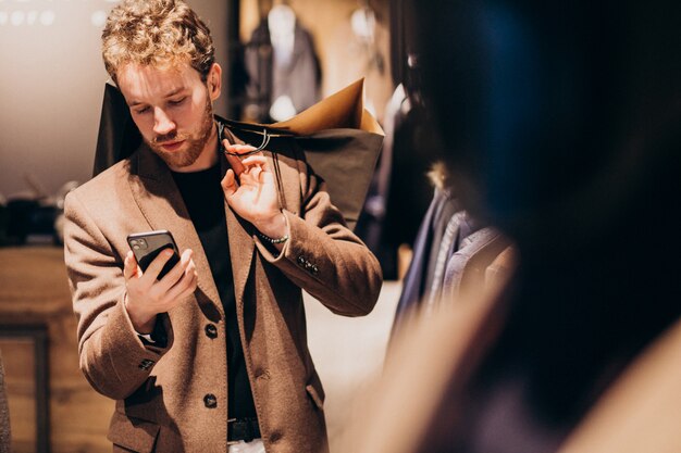 Joven en la tienda de ropa masculina hablando por teléfono