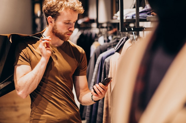 Joven en la tienda de ropa masculina hablando por teléfono