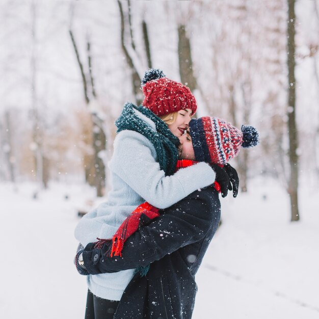 Joven tierna pareja abrazándose en las nevadas