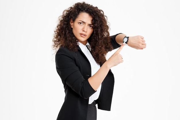 Foto gratuita joven tierna y rizada mirando el reloj y preocupada de que la tarde