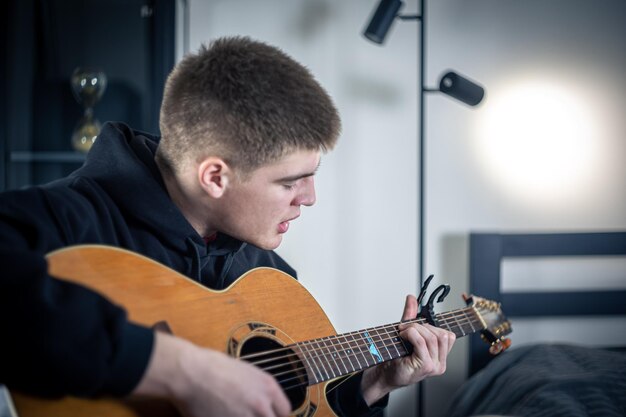 Un joven toca la guitarra acústica y canta.