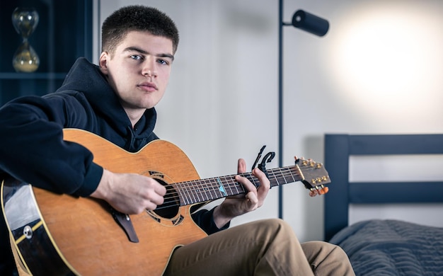 Un joven toca la guitarra acústica y canta.