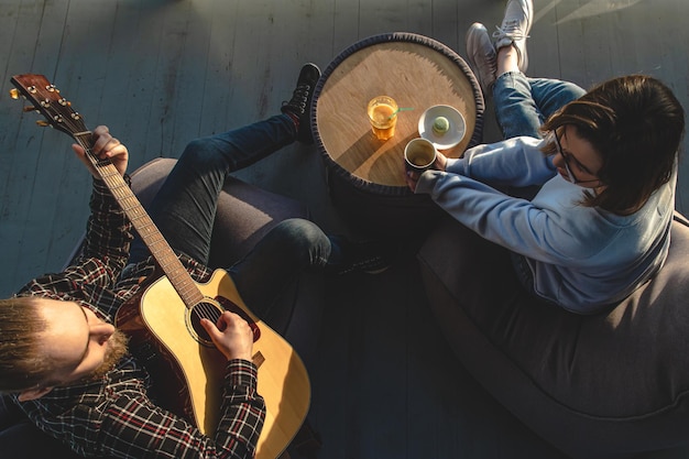 Un joven toca la guitarra para la vista superior de una chica