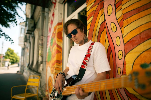 Foto gratuita joven tocando la guitarra en una calle.