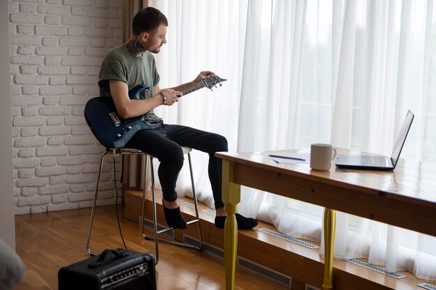 Joven tocando la guitarra en casa