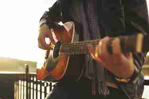 Foto gratuita joven tocando la guitarra en el lago