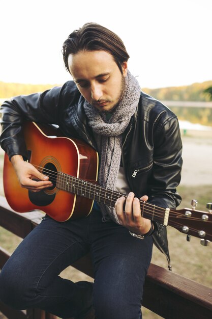 Joven tocando la guitarra en el lago