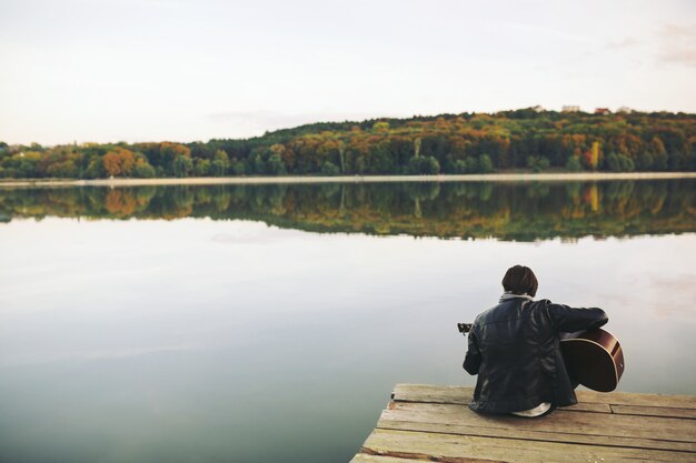 Joven tocando la guitarra en el lago