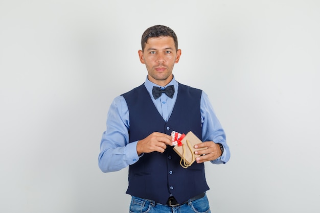 Joven tomando presente de bolsa de papel en traje