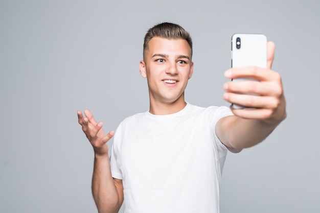 Joven tomar selfie aislado en gris