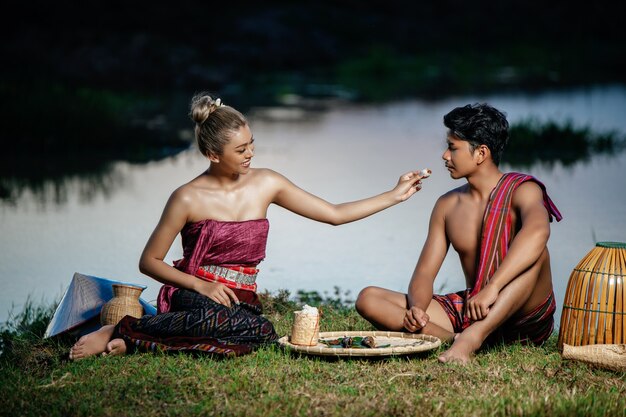 Joven en topless vistiendo taparrabos en estilo de vida rural y joven mujer bonita, pareja de agricultores tiene cena