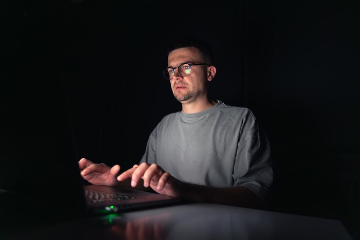 Foto gratuito el joven trabaja en la computadora por la noche.