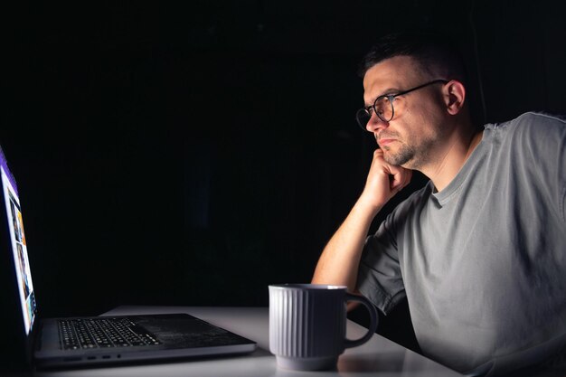 El joven trabaja en la computadora por la noche.