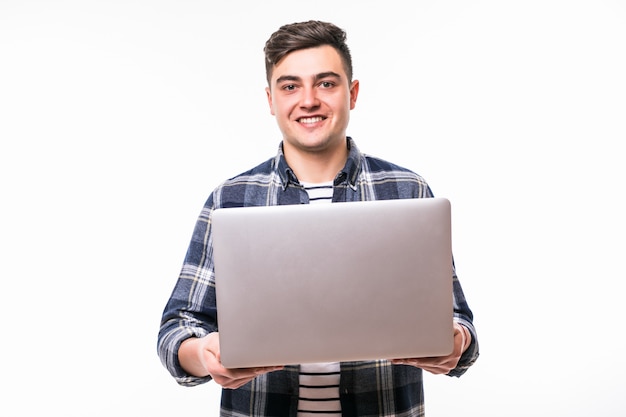 Joven trabaja con la computadora portátil delante de la pared blanca del estudio