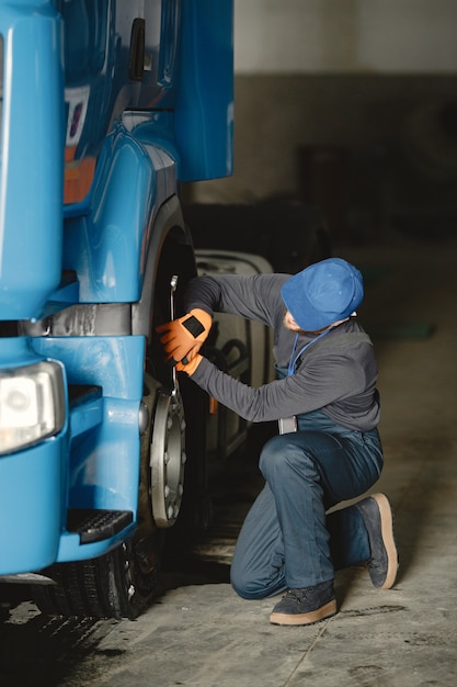 Un joven trabajador controla la rueda. Mal funcionamiento del camión. Trabajo de servicio.