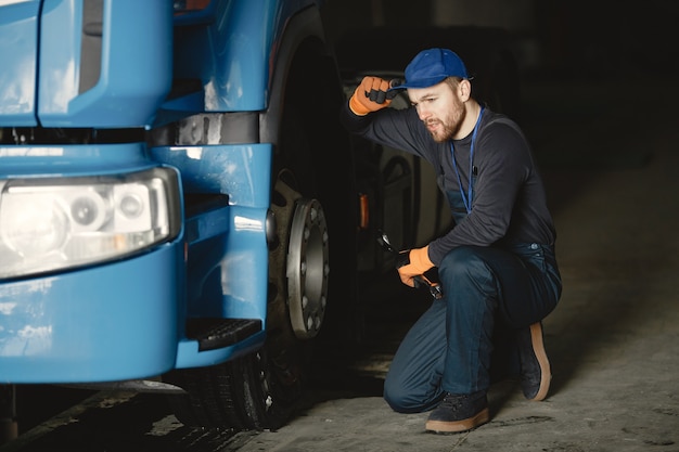 Un joven trabajador controla la rueda. Mal funcionamiento del camión. Trabajo de servicio.