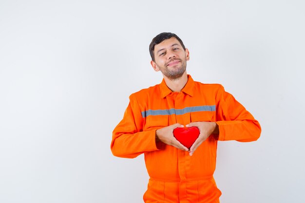 Joven trabajador con corazón rojo en uniforme y alegre.