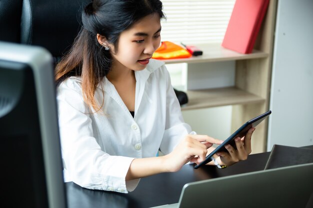 Joven trabajadora disfruta usar tableta en la oficina