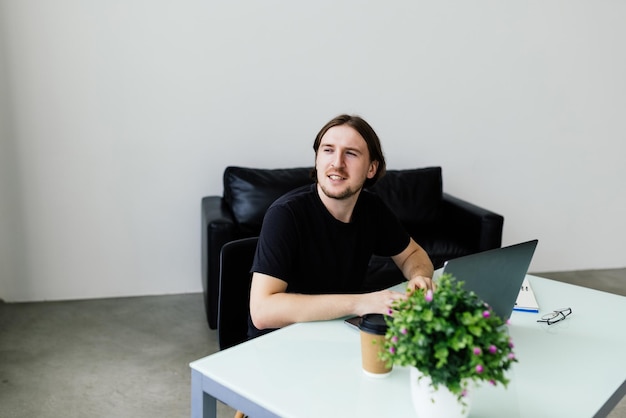 Joven trabajando en casa con laptop y papeles en el escritorio