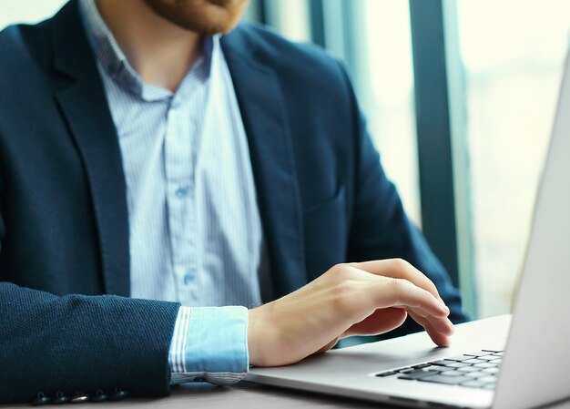 Joven trabajando con la computadora portátil, las manos del hombre en la computadora portátil, persona de negocios en el lugar de trabajo