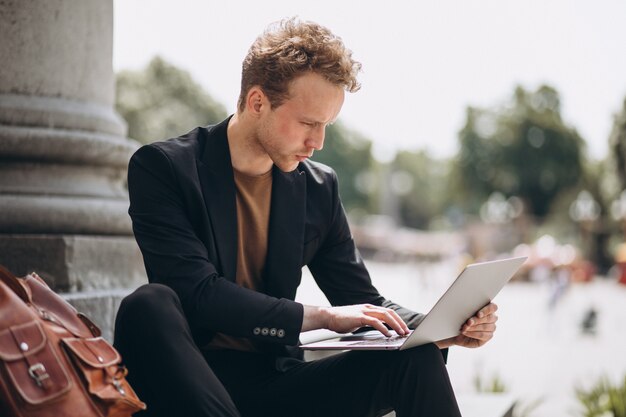 Joven trabajando en una computadora por la universidad