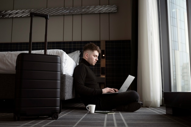 Joven trabajando en su computadora portátil en una habitación de hotel