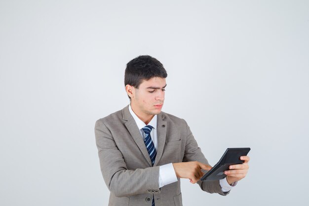 Joven en traje formal sosteniendo la calculadora, haciendo algunas operaciones en ella