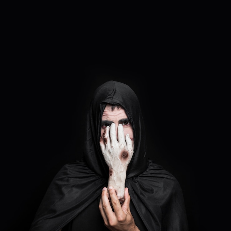 Foto gratuito joven en traje de halloween con capucha con mano de cadáver