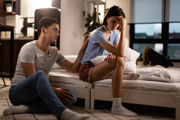 Joven tratando de reconciliarse con su novia después de una discusión en el dormitorio