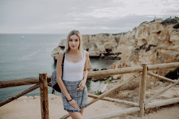 Joven turista europea con una mochila mirando el mar