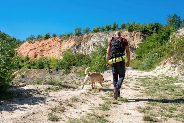 Joven turista varón caucásico explorando hermosos lugares con su perro