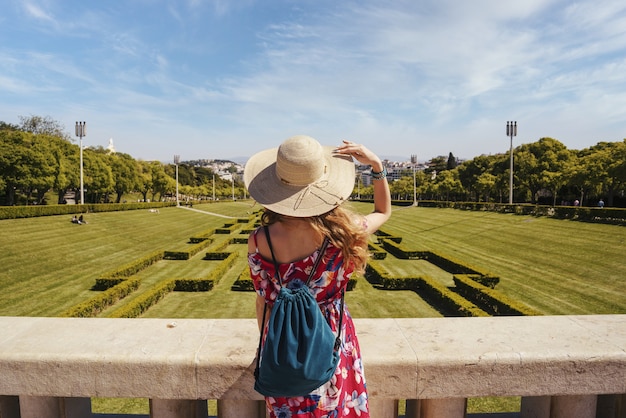 Foto gratuita joven turista en un vestido floral rojo en el parque eduardo vii bajo la luz del sol en portugal