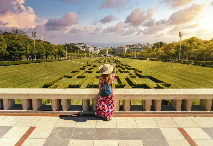 Foto gratuito joven turista en un vestido floral rojo en el parque eduardo vii bajo la luz del sol en portugal