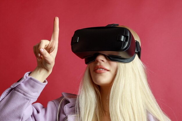 La joven usa gafas VR y señala con el dedo el fondo rojo