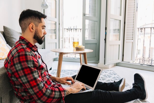 Joven usando la computadora portátil en el piso