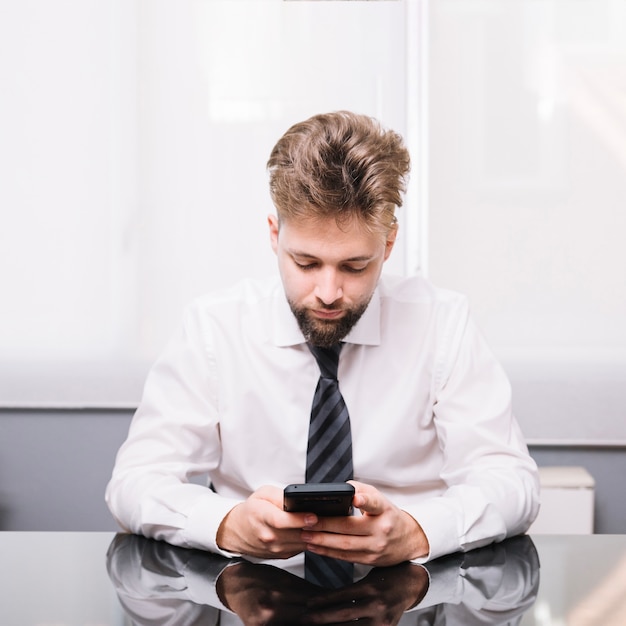 Foto gratuita joven usando teléfono en la oficina