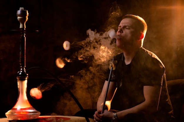 Joven vaping de una pipa de agua en un bar.