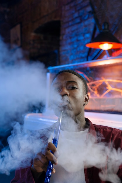 Joven vaping de una pipa de agua en un bar.