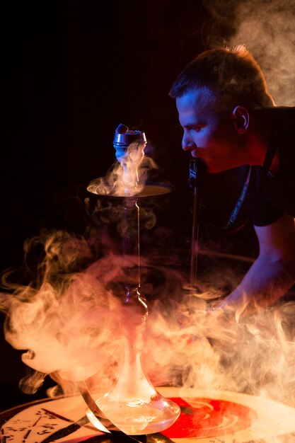 Joven vaping de una pipa de agua en un bar.