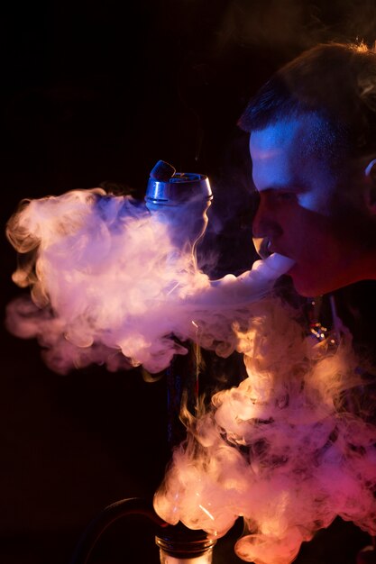 Joven vaping de una pipa de agua en un bar.