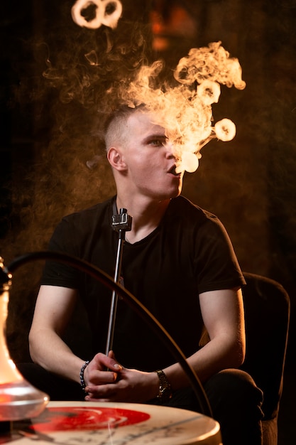 Joven vaping de una pipa de agua en un bar.