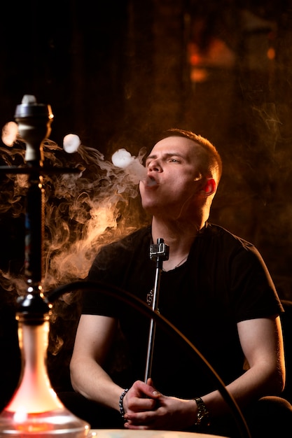 Joven vaping de una pipa de agua en un bar.