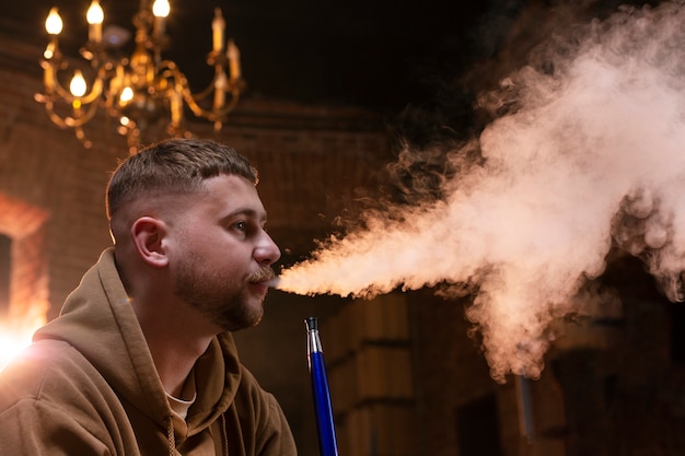 Foto gratuita joven vaping de una pipa de agua en un bar.